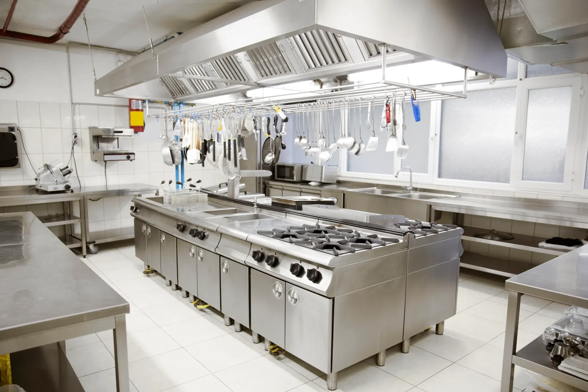 A kitchen with many stainless steel appliances and white tile.