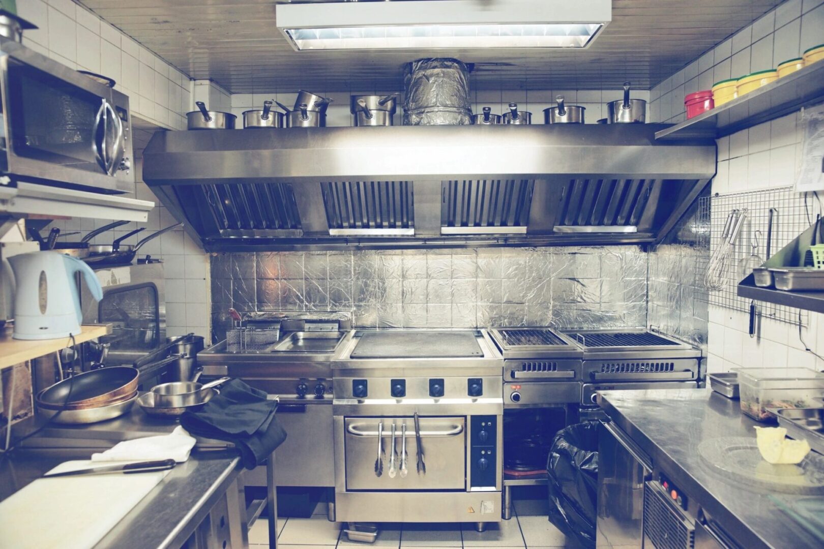 A kitchen with many pots and pans on the counter.